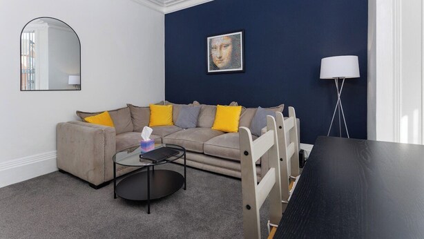 Ein Wohnzimmer mit einer Couch, einem runden Couchtisch, einer Lampe und einem Gemälde an der Wand.