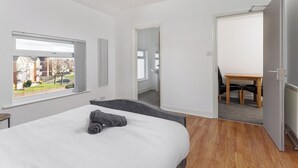Ein modernes Schlafzimmer mit einem großen Bett, einem Fenster mit Blick, einer Tür zu einem Badezimmer und einem kleinen Tisch mit Stühlen.