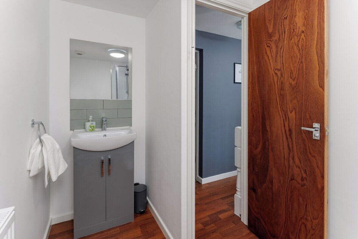 Une salle de bain avec un lavabo blanc, un miroir et un meuble gris.