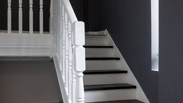 A staircase with white balusters and dark steps, leading to a landing with a small window.