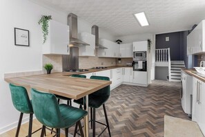 A modern kitchen with a central island, bar stools, and a herringbone floor pattern.