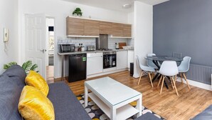 Ett modernt kök med en matplats, en soffa med kuddar och ett litet bord.