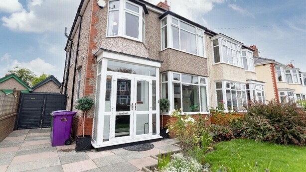 A residential property with a front garden, a conservatory, and a black gate.