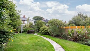 A well-maintained garden with a curved pathway, a wooden bench, and various plants.