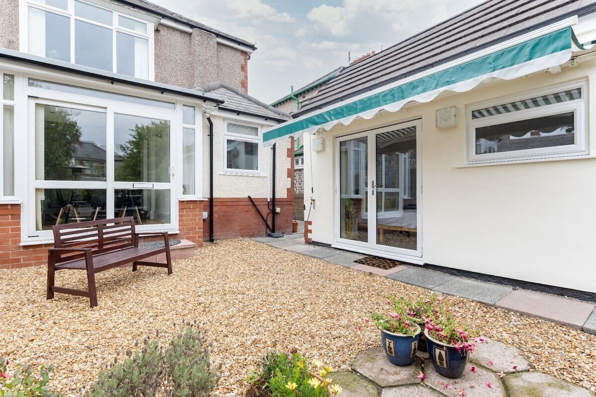 A residential property with a patio area, a bench, and potted plants.