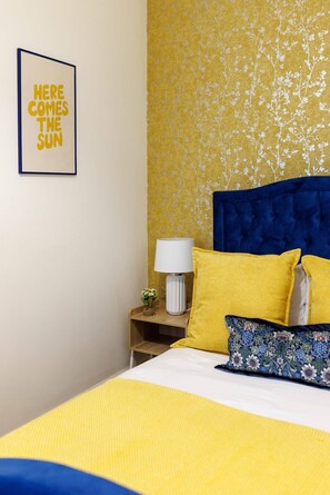 Ein Hotelzimmer mit einem Bett, einem Nachttisch, einer Lampe und einem gerahmten Bild an der Wand.