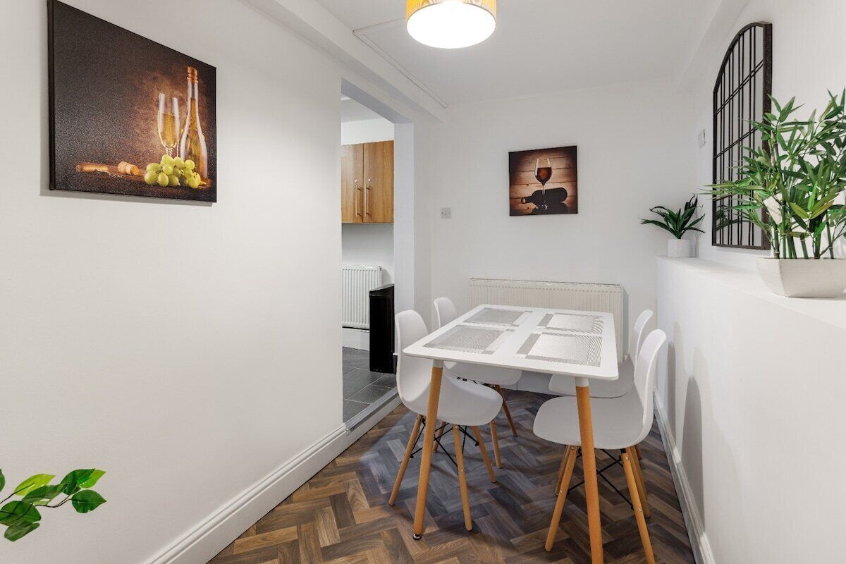 A modern dining area with a white table and chairs, a radiator, and a potted plant.
