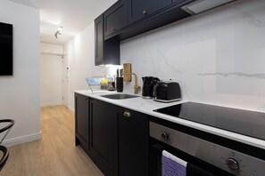 A modern kitchen with dark cabinets, a white countertop, and a built-in dishwasher. - Flatzy City Centre Retreat  Sleeps 8  2 baths (Liverpool)