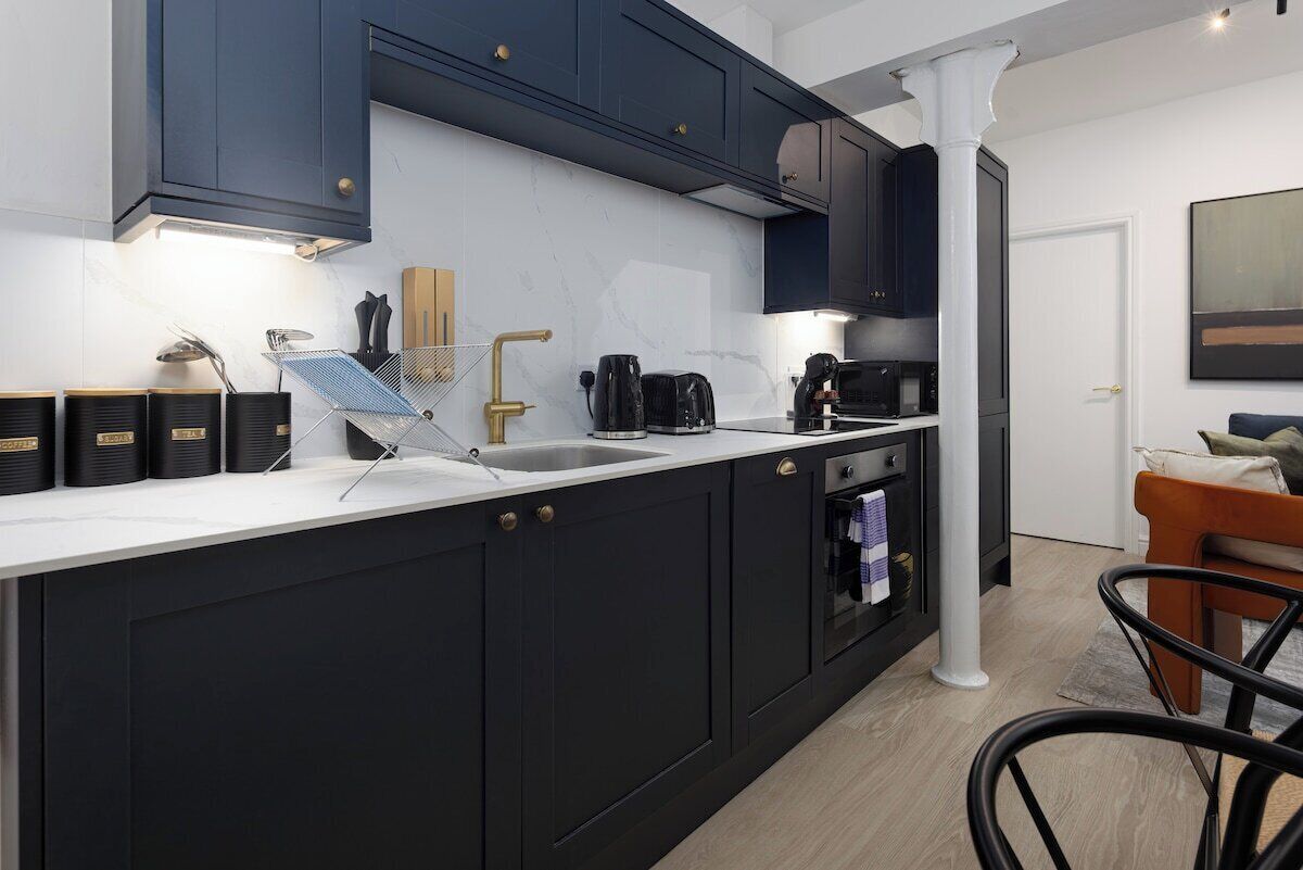 A modern kitchen with dark cabinetry, a white countertop, and a built-in oven.