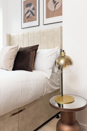 Un lit avec une tête de lit, une lampe de chevet et une table ronde avec une lampe.