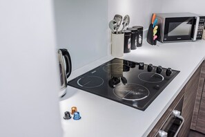 A modern kitchen with a black stovetop, a microwave, and a set of utensils. - Flatzy - City Centre | 2 Bathrooms | Free Parking (Liverpool)