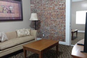 Ein Wohnzimmer mit Backsteinwand, einer Couch, einem Couchtisch und einer Lampe.