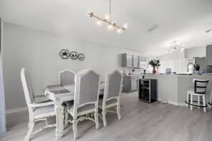 A modern kitchen with a central island, white cabinetry, and a dining area with ornate chairs. - Cozy 3-bedroom house in perfect Ocala with AC for relaxing stays (Ocala)