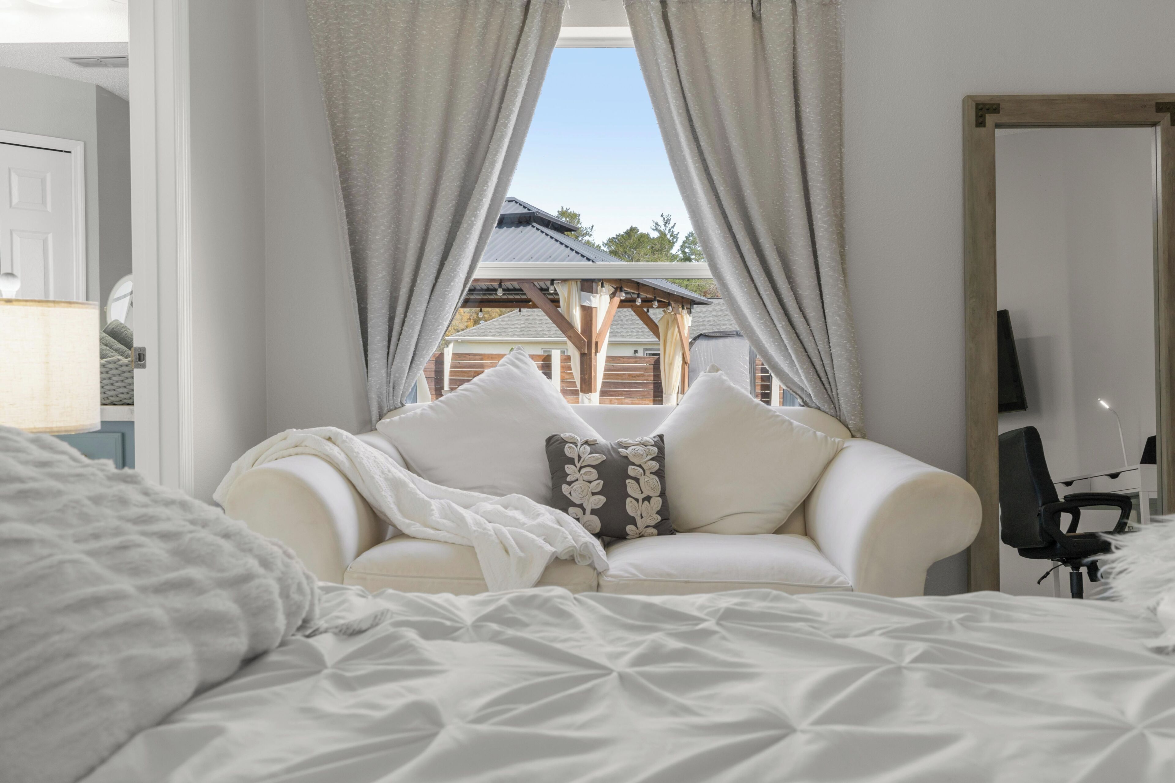 Une chambre à coucher avec un lit, un canapé blanc et un téléviseur.