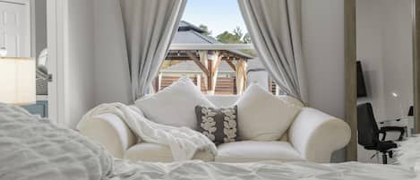 A bedroom with a bed, a white sofa, and a TV.