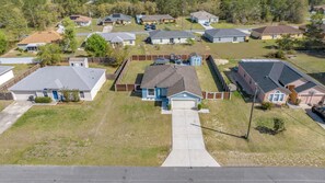 A residential area with multiple houses, a central driveway, and a fenced yard. - Cozy 3-bedroom house in perfect Ocala with AC for relaxing stays (Ocala)