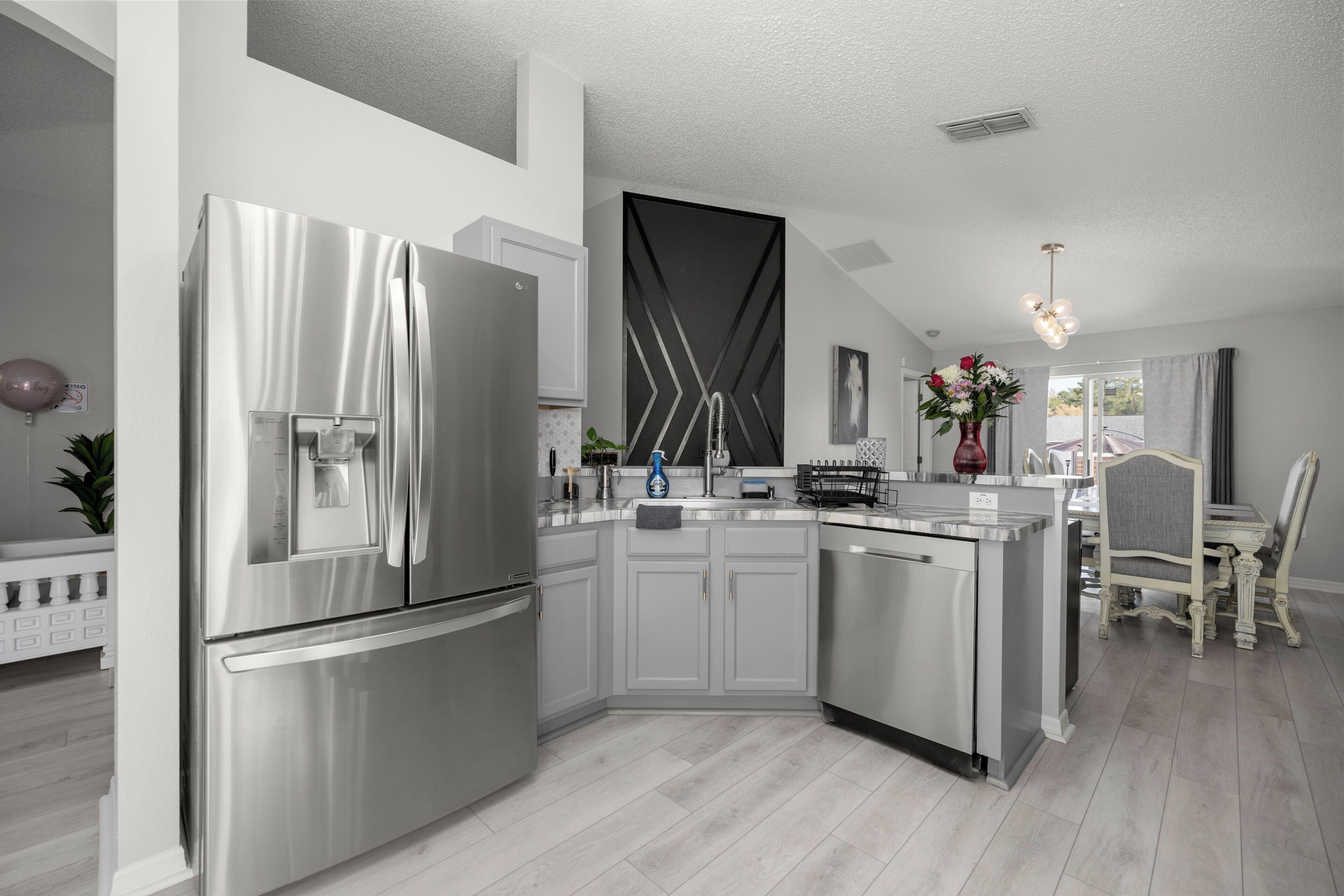 A modern kitchen with stainless steel appliances, a built-in island, and a dining area with a chair and table.