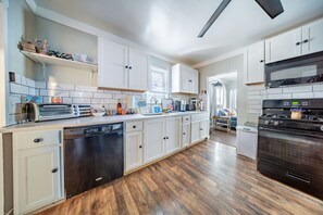 Une cuisine moderne avec des meubles blancs, un lave-vaisselle, une cuisinière et un four à micro-ondes.