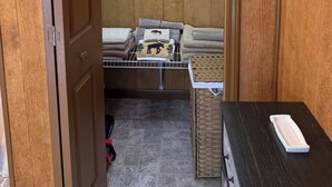 Et værelse med en trædør, et lille bord med en hvid bakke og en fletkurv.