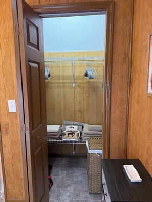 Ein Zimmer mit Holztür, einem kleinen Tisch mit weißem Tablett und einem Korbwäschekorb.