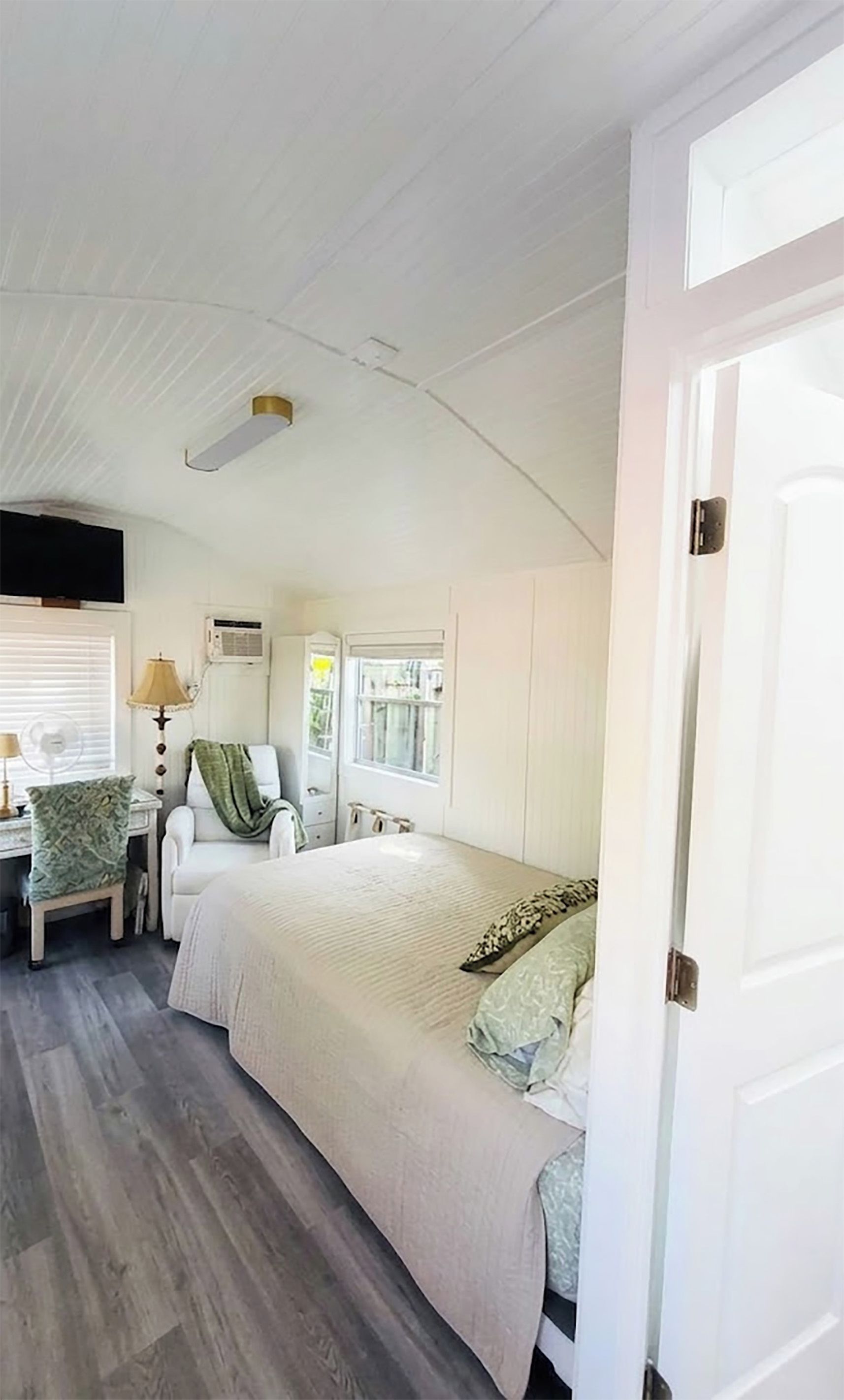 A bedroom with a bed, a chair, a lamp, and a window.