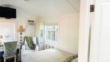 A bedroom with a bed, a chair, a lamp, and a window.