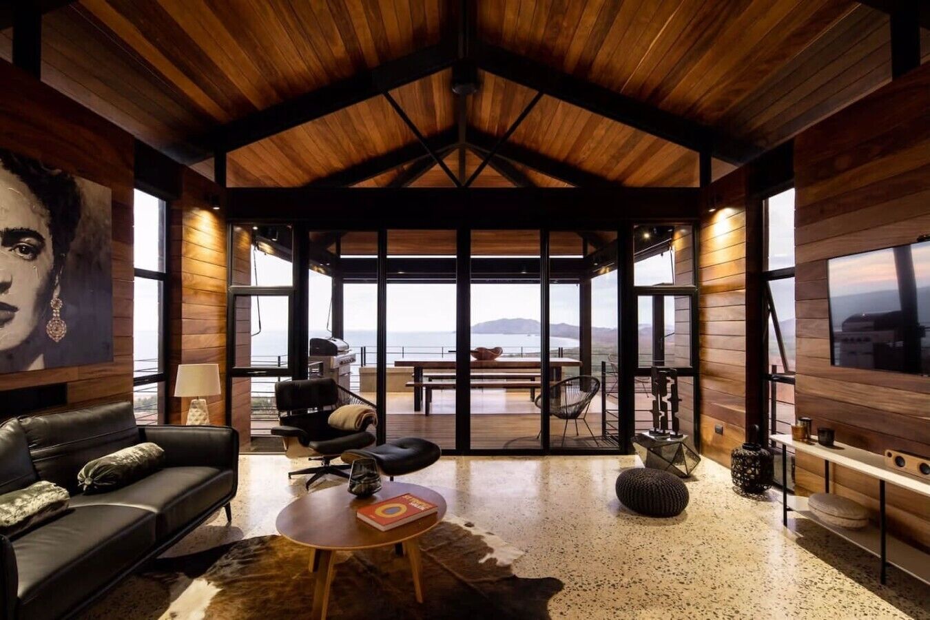 Amplia sala de estar con techo alto, un sofá de cuero, una mesa de centro redonda y vistas al exterior.