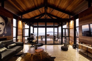 A spacious living area with a high ceiling, a leather sofa, a round coffee table, and a view of the outdoors. - Hottub w/Elite Ocean View! | Chef`s Kitchen | 3 Pools | Personal Concierge (Tamarindo)