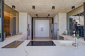 A modern kitchen with a central island, built-in appliances, and a large window. - Hottub w/Elite Ocean View! | Chef`s Kitchen | 3 Pools | Personal Concierge (Tamarindo)