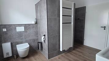 Ein modernes Badezimmer mit Toilette, Bidet und Duschbereich.