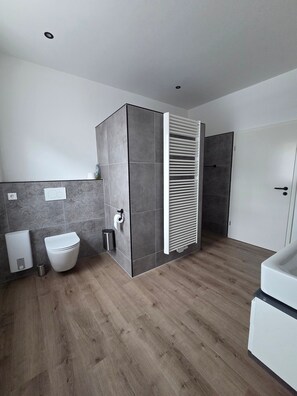 Ein modernes Badezimmer mit Toilette, Bidet und Duschbereich.