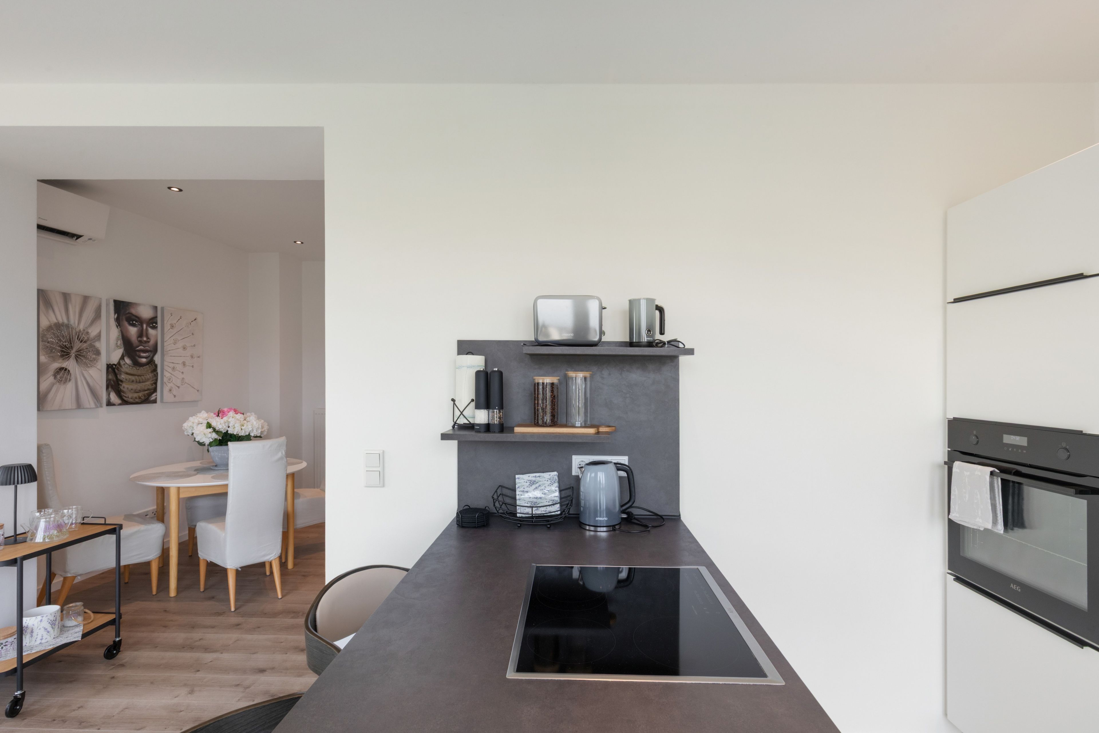 A modern kitchen with a built-in stovetop, a coffee machine, and a kettle on the countertop.