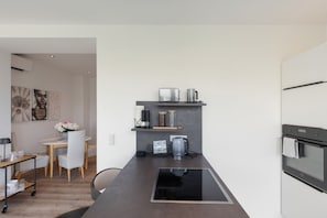 A modern kitchen with a built-in stovetop, a coffee machine, and a kettle on the countertop.