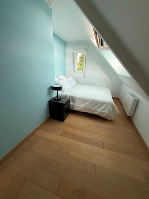 A bedroom with a sloped ceiling, a bed, a bedside table, and a window. - House with ocean views near the GR34 and Royau Beach (Trévou-Tréguignec)