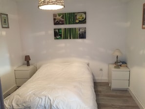Et soveværelse med en seng, to sengeborde, en lampe og billedkunst på væggen.