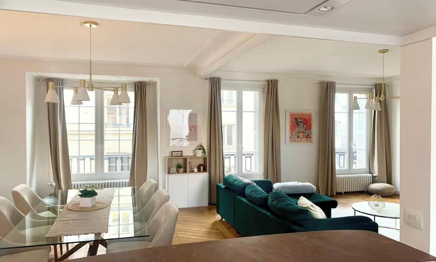 A modern living room with a dining area, large windows, and a view of the street.