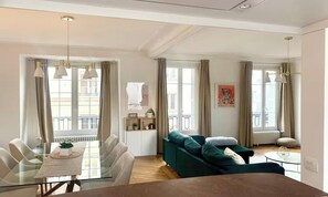 Ein modernes Wohnzimmer mit Essbereich, großen Fenstern und Blick auf die Straße.