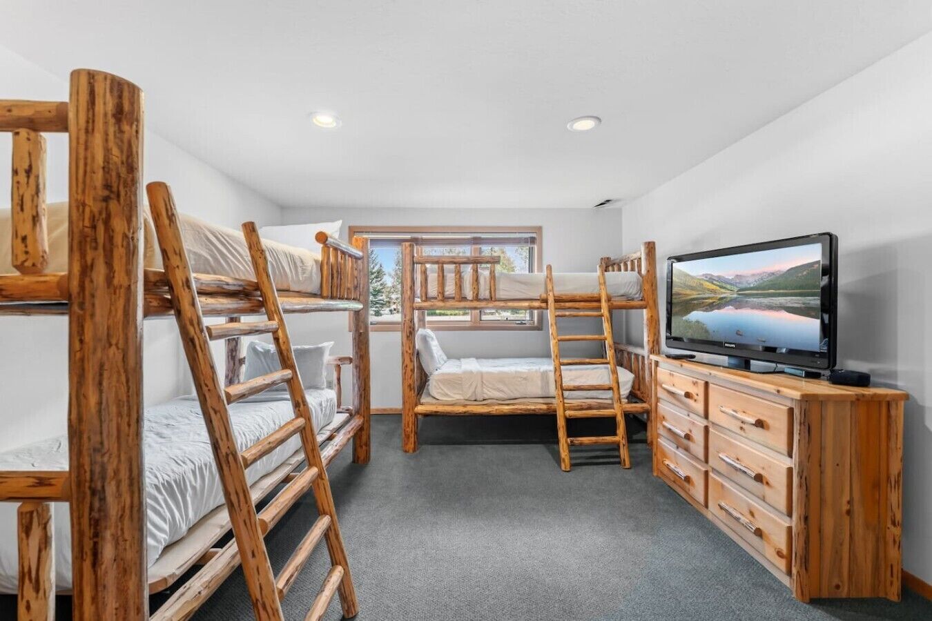 Een kamer met stapelbedden, een televisie en een houten dressoir.