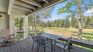 A covered outdoor deck with a table and chairs, overlooking a grassy area with trees. - Golf Course Views W/ EagleVail Amenities (avon)