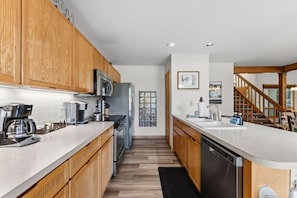 A modern kitchen with wooden cabinets, stainless steel appliances, and a large island with a sink. - Golf Course Views W/ EagleVail Amenities (avon)