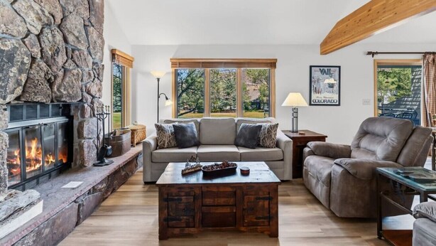 A living room with a stone fireplace, a sofa set, a leather armchair, and a coffee table. - Golf Course Views W/ EagleVail Amenities (avon)