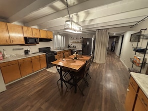 A kitchen with wooden cabinets, a dining table with placemats, a stove, and a refrigerator.