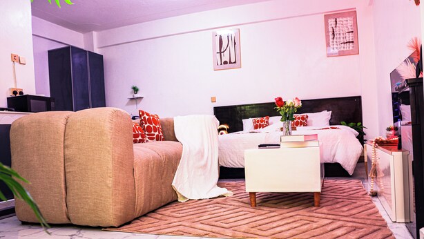 Un dormitorio moderno con sofá, cama, mesita de noche y pequeño escritorio.