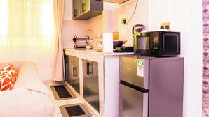 Cozinha compacta com geladeira, micro-ondas e uma pia pequena.
