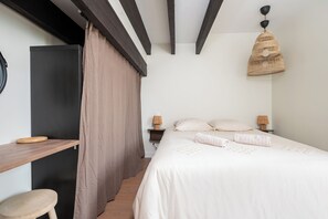 A bedroom with a bed, bedside lamps, a wooden desk, a chair, and a hanging light fixture. - 5 passengers • Air Conditioning • Free parking • Downtown on foot (Albi)