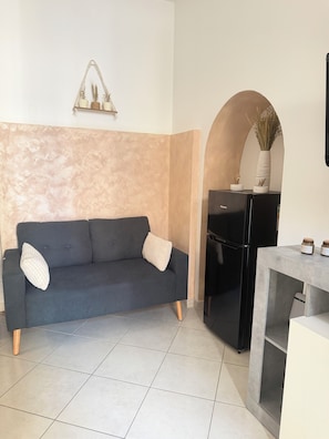 A modern living room with a dark grey sofa, a small table, and a black cabinet. - Al Vicolèt Apartment - Self-Check-In (Vercelli)