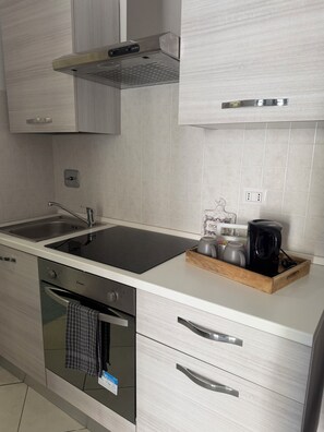 Una cucina moderna con lavandino in acciaio inossidabile, forno integrato e macchina da caffè sul piano di lavoro.