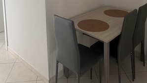 A dining area with a table and chairs, framed pictures on the wall, and a light switch.