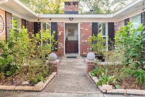 A brick house with a front porch, a chimney, and a door leading to the interior. - Enclosed Pool & Sauna Retreat Near Beaches (Fort Walton Beach)