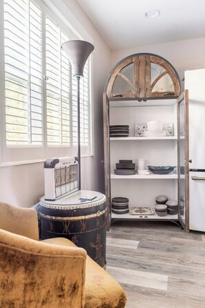 A room with a sofa, a lamp, a pet carrier, and a wooden cabinet with shelves. - Enclosed Pool & Sauna Retreat Near Beaches (Fort Walton Beach)